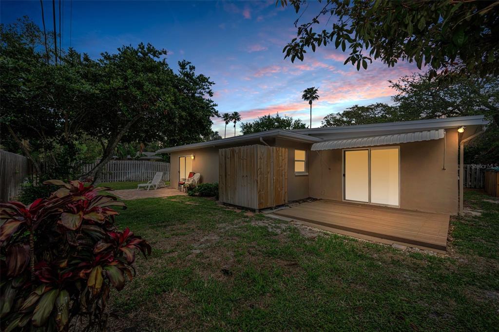 The backyard of a single-story house features a wooden deck, patio, and privacy enclosure — 253 PARK CIRCLE S, DUNEDIN, FL