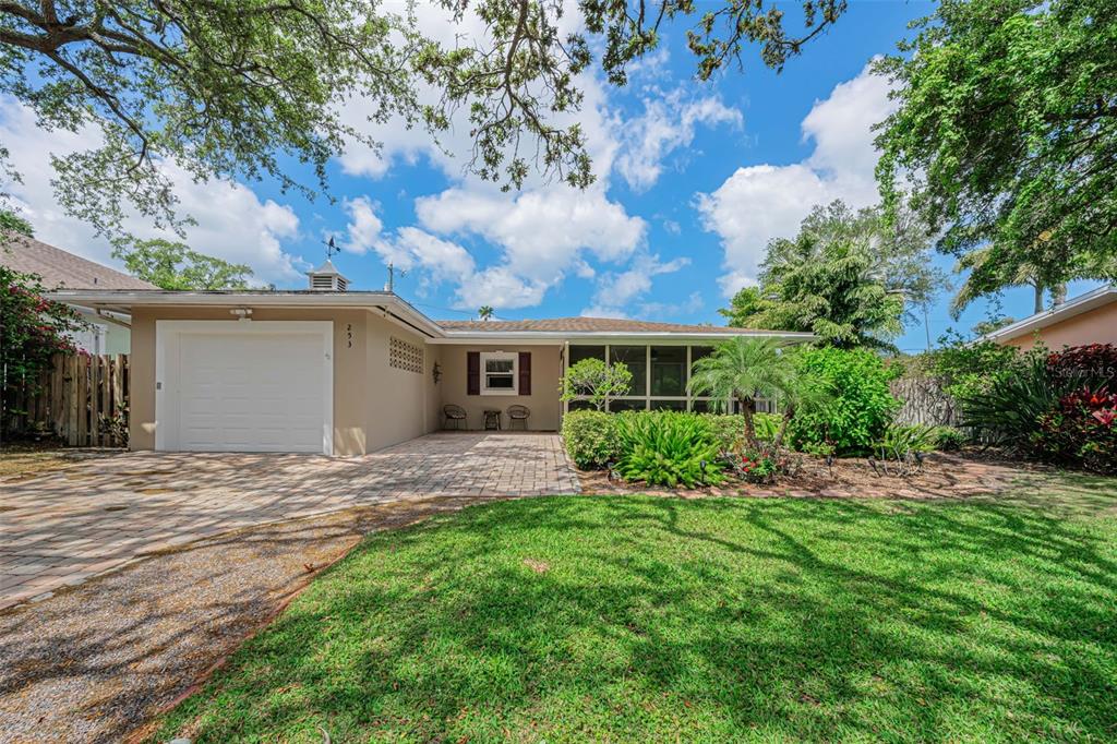 A single-story house with a white garage door, paved driveway, and a screened-in front porch — 253 PARK CIRCLE S, DUNEDIN, FL