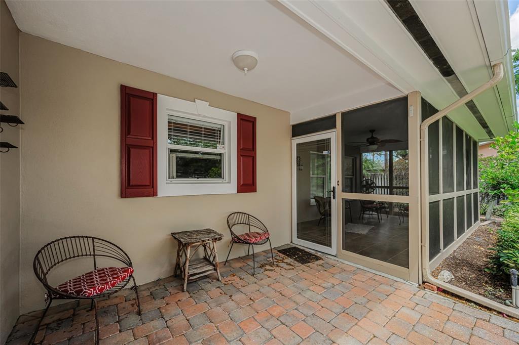 A paved patio features two metal chairs, a small side table, and a screened-in porch — 253 PARK CIRCLE S, DUNEDIN, FL
