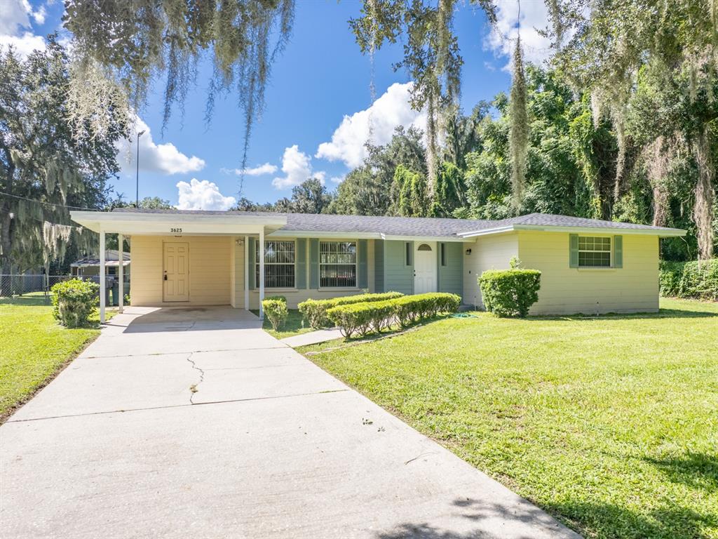 A single-story house with a carport, light-colored siding, and a concrete driveway under blue skies — 3625 E GANDY ROAD, BARTOW, FL