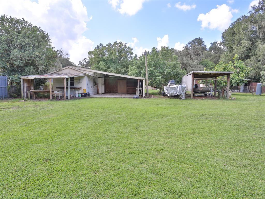 A backyard view of a house with a covered patio and a separate detached carport — 3625 E GANDY ROAD, BARTOW, FL