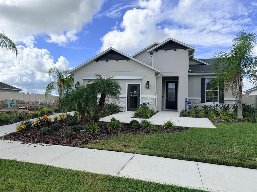 A modern single-story house with a gray stucco exterior, stone accents, and a landscaped front yard — 2442 PINWHERRY STREET NW, PALM BAY, FL