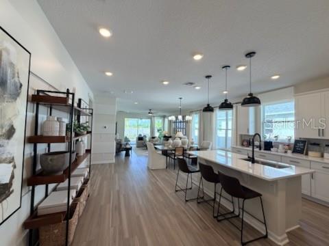 An open-concept kitchen and living area featuring a large island, pendant lighting, and wood flooring — 2442 PINWHERRY STREET NW, PALM BAY, FL