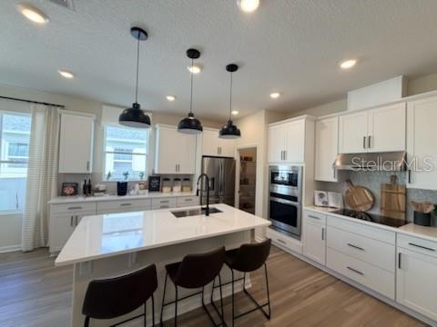 A modern kitchen features white cabinetry, a large center island with pendant lights, and appliances — 2442 PINWHERRY STREET NW, PALM BAY, FL