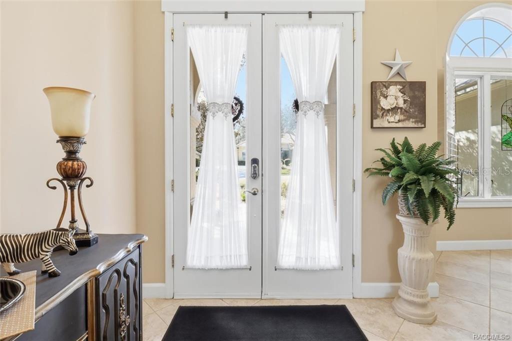 An entryway features double glass doors with white curtains, a side table, and a potted plant — 3033 N CAVES VALLEY PATH, LECANTO, FL