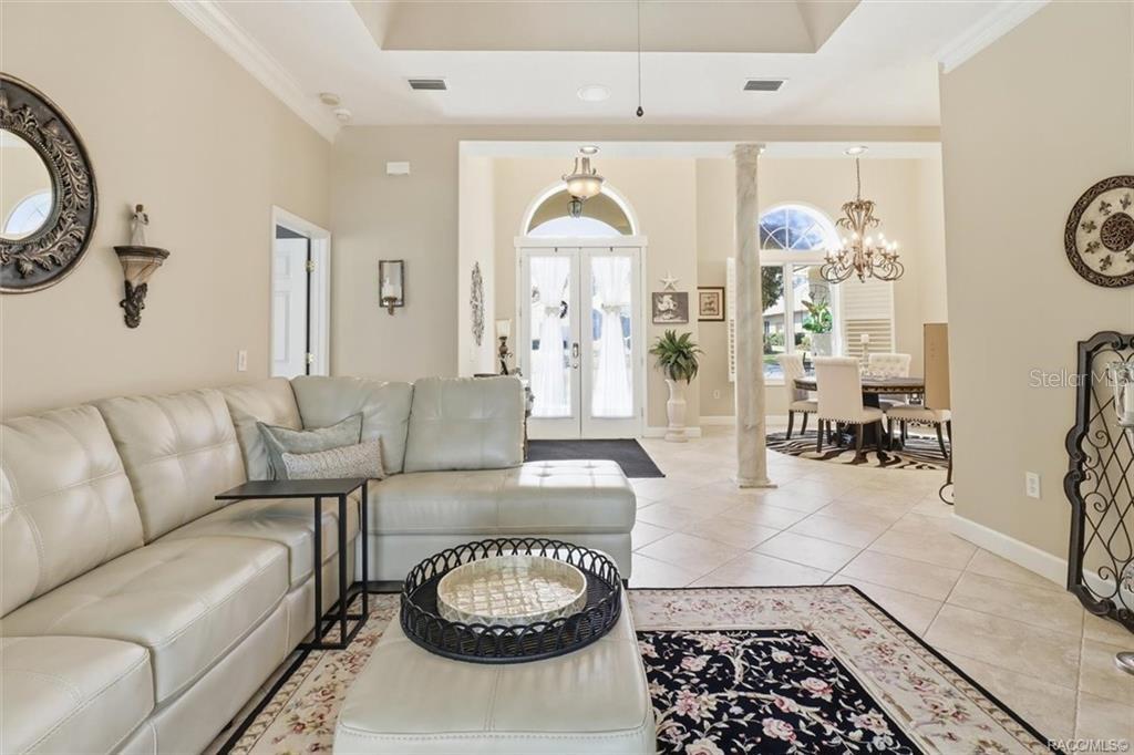 A living room with a light-colored sectional sofa, tile floors, and an open dining area — 3033 N CAVES VALLEY PATH, LECANTO, FL