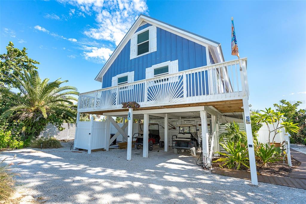 A blue stilt house with a white balcony and two golf carts parked underneath — 210 BOCILLA DRIVE, PLACIDA, FL