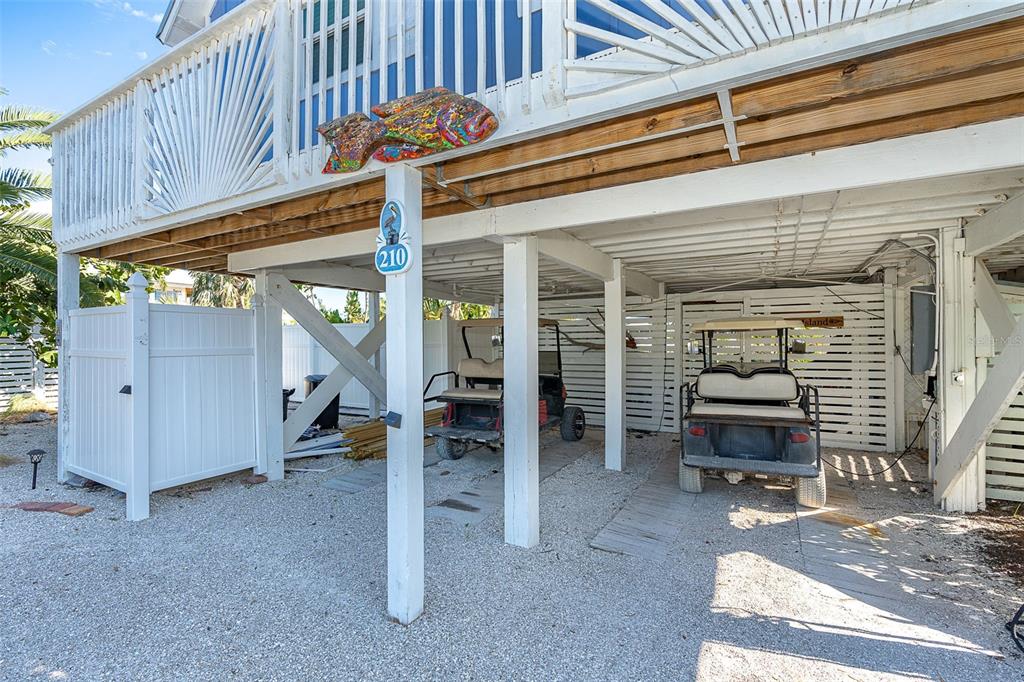 The ground level of a stilt house features two golf carts parked on gravel — 210 BOCILLA DRIVE, PLACIDA, FL