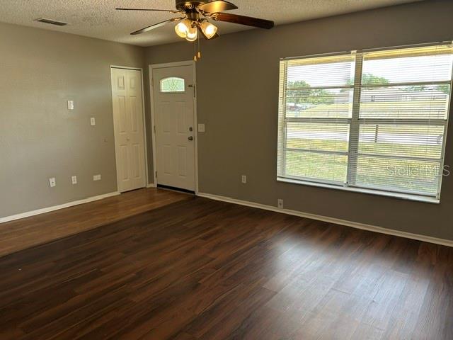 A living room features dark wood-look flooring, a ceiling fan, and a large window — 6224 STANWIN DRIVE, APOPKA, FL