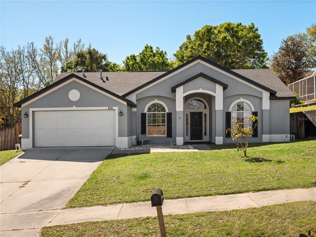 A single-story gray house with a two-car garage and a front lawn — 834 HIGH POINTE CIRCLE, MINNEOLA, FL