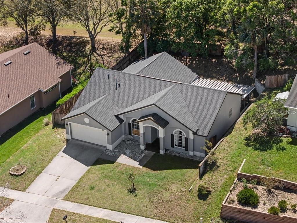 An aerial view of a single-story gray house with a two-car garage and shingled roof — 834 HIGH POINTE CIRCLE, MINNEOLA, FL