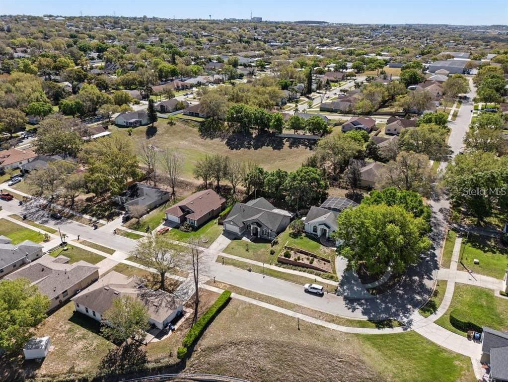 An aerial view shows a suburban neighborhood with houses, trees, and a large grassy lot — 834 HIGH POINTE CIRCLE, MINNEOLA, FL