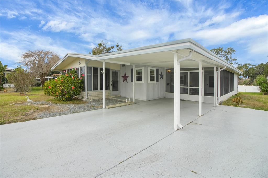 A single-story mobile home with a carport, screened-in porch, and a light-colored exterior — 11 ORANGEWOOD DRIVE, FRUITLAND PARK, FL