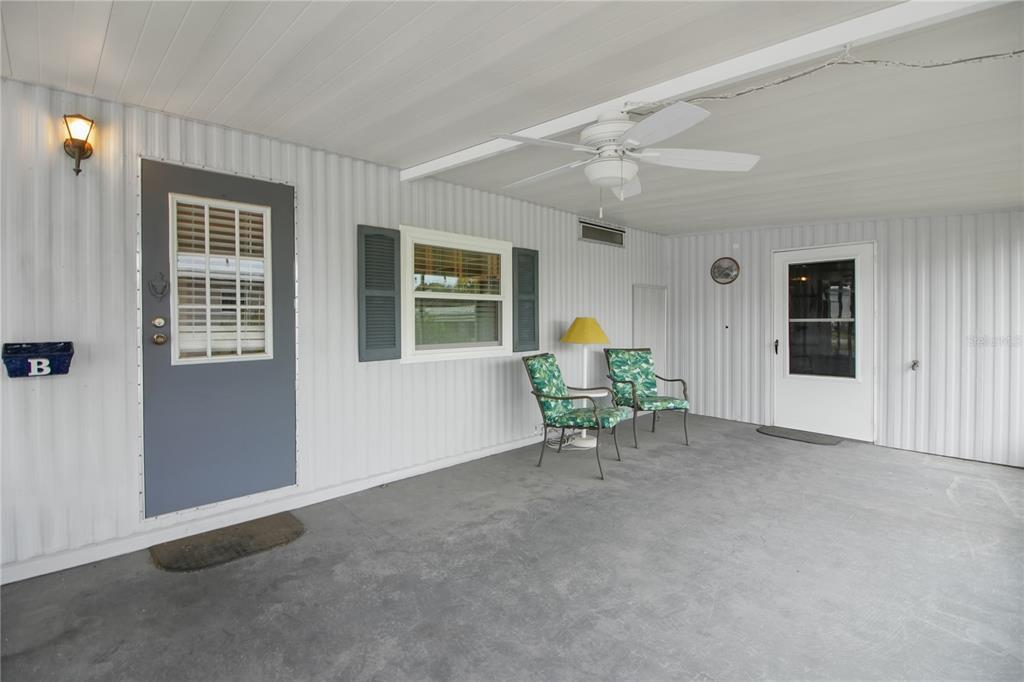 A covered patio features a concrete floor, two chairs, a ceiling fan, and two doors — 11 ORANGEWOOD DRIVE, FRUITLAND PARK, FL