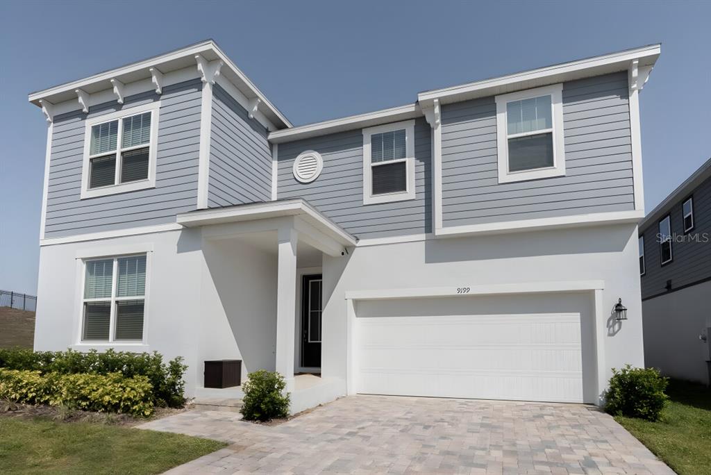 A two-story house with a white stucco lower level, blue siding, and a two-car garage — 9199 BREEZE MIST TERRACE, DAVENPORT, FL