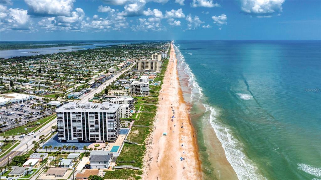 An aerial view shows a coastal beach, ocean, and nearby residential and commercial buildings — 1239 OCEAN SHORE BOULEVARD UNIT 2E5, ORMOND BEACH, FL