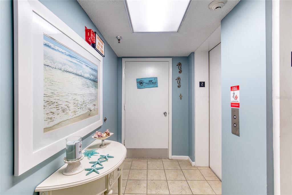 A hallway features a console table with starfish decor, a framed beach print, and an elevator — 1239 OCEAN SHORE BOULEVARD UNIT 2E5, ORMOND BEACH, FL