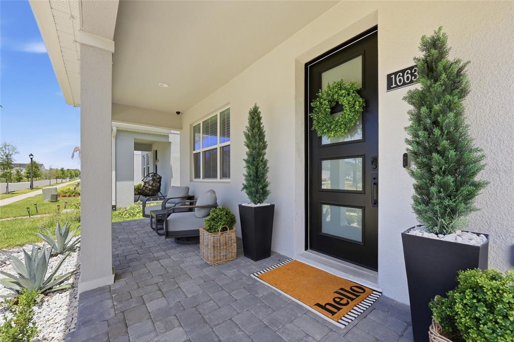 A bright entryway features a black front door, wood console table, and a staircase railing — 1663 CROWNCREST DRIVE, APOPKA, FL