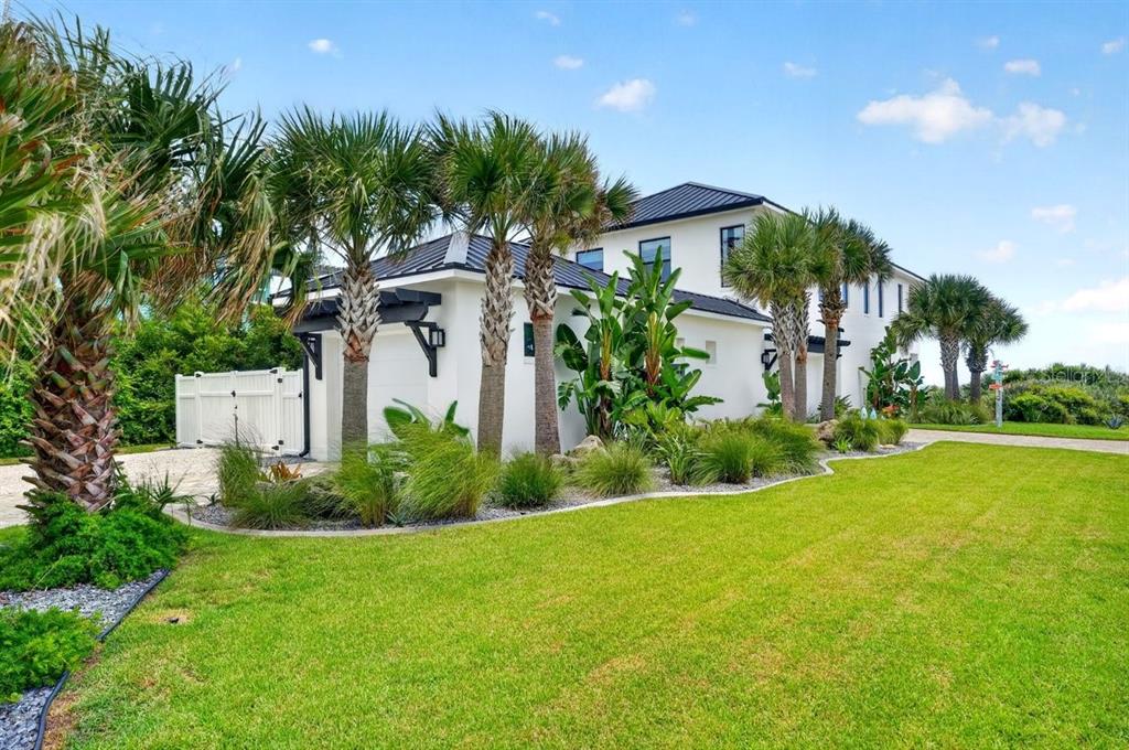 A modern white two-story house with a black metal roof and palm trees — 2574 S OCEAN SHORE BOULEVARD, FLAGLER BEACH, FL