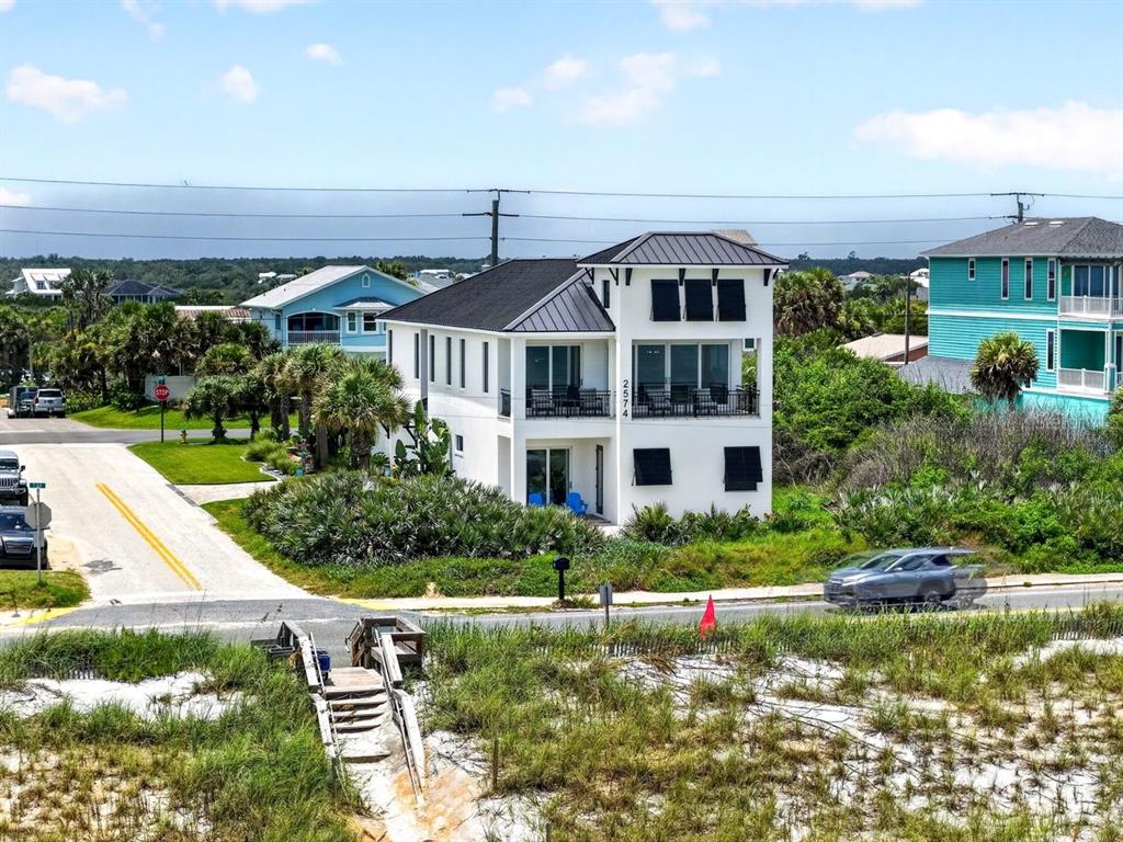 An aerial view shows a white two-story house with a metal roof near the beach — 2574 S OCEAN SHORE BOULEVARD, FLAGLER BEACH, FL