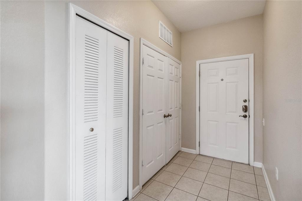An entryway features beige walls, tiled flooring, a front door, and two sets of closet doors — 2821 E ALMATON LOOP UNIT 401, KISSIMMEE, FL