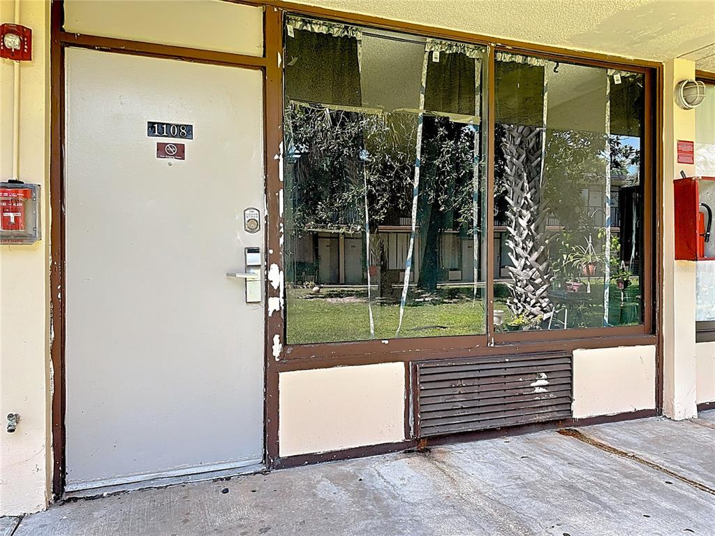 A ground-level hotel room exterior features a gray door, large window, and wall-mounted air conditioner — 7900 S ORANGE BLOSSOM TRAIL UNIT 1108, ORLANDO, FL