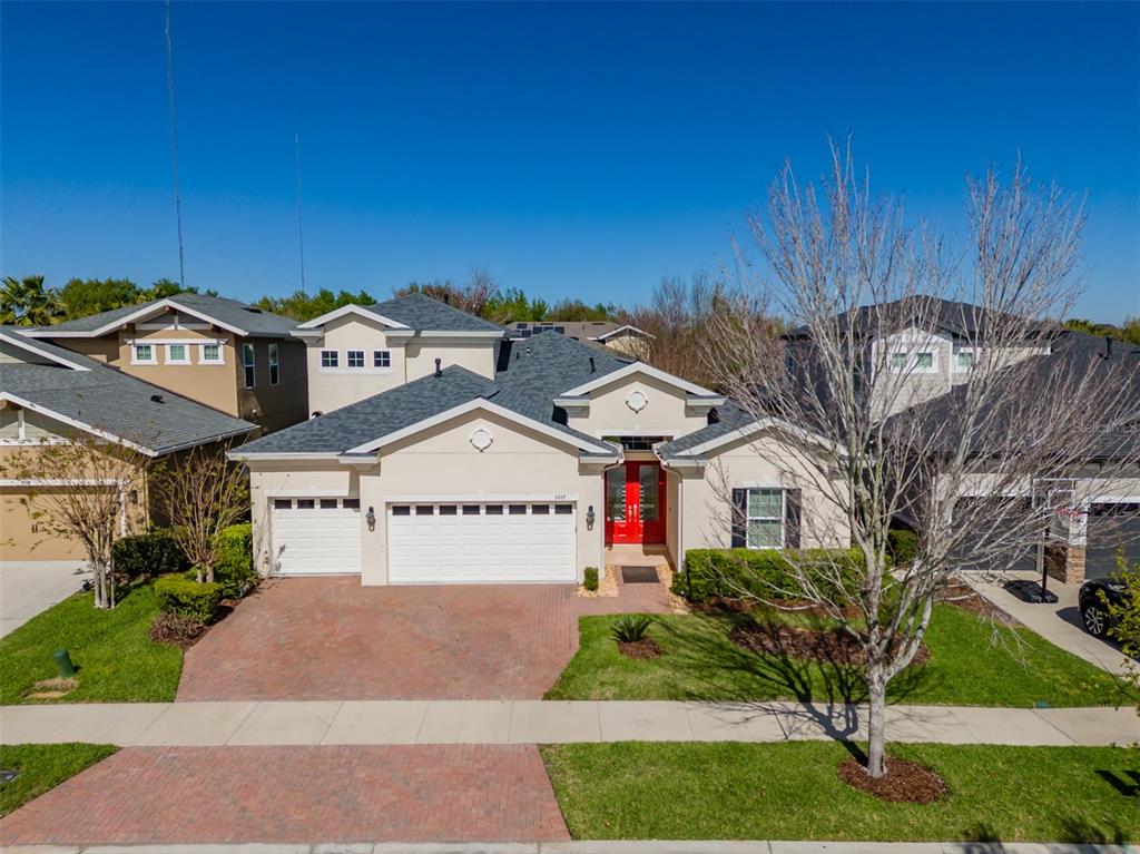 An exterior view of a single-story suburban house with a brick driveway and red doors — 5927 JASPER GLEN DRIVE, LITHIA, FL