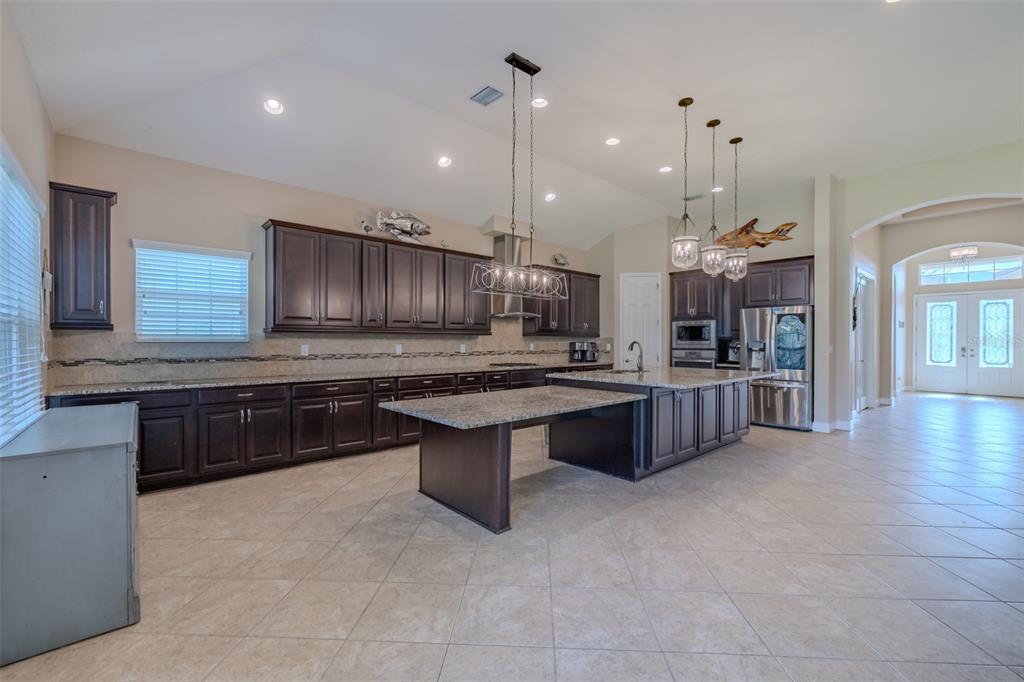 A spacious kitchen features dark wood cabinetry, granite countertops, a large island, and tile flooring — 5927 JASPER GLEN DRIVE, LITHIA, FL