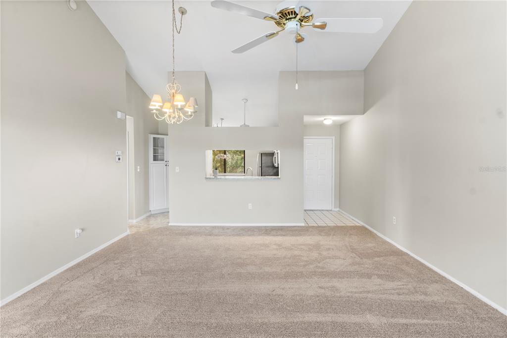 A living room with beige carpet, a vaulted ceiling, a ceiling fan, and a chandelier — 5685 MARINA DRIVE UNIT 4, SEBASTIAN, FL