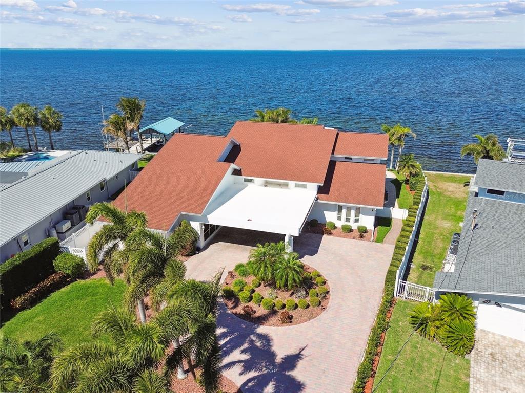 An aerial view shows a waterfront house with a red roof and a circular driveway — 119 CARLYLE CIRCLE, PALM HARBOR, FL