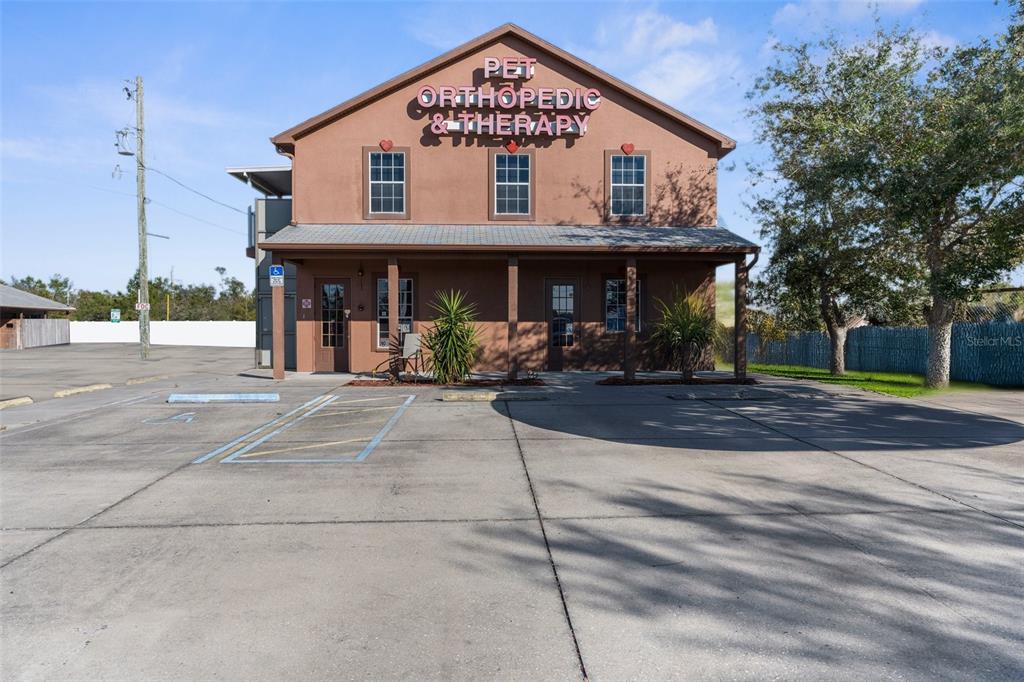 A two-story brown commercial building with a sign reading Pet Orthopedic & Therapy — 7044 COMMERCIAL WAY, WEEKI WACHEE, FL