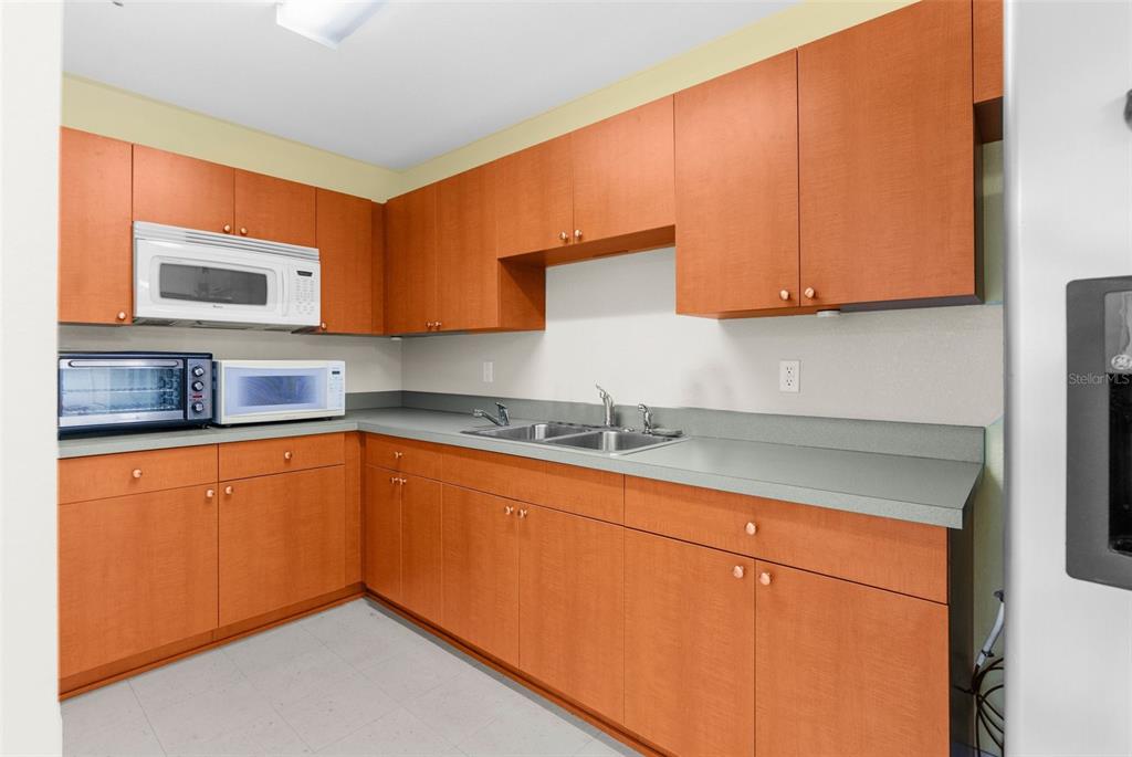 A kitchen features wood cabinets, a gray countertop, a double sink, and several small appliances — 7044 COMMERCIAL WAY, WEEKI WACHEE, FL