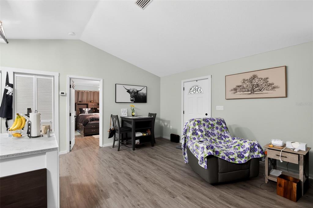 A living area features light gray walls, wood-look flooring, a small dining set, and furniture — 7390 NW 142ND STREET, TRENTON, FL