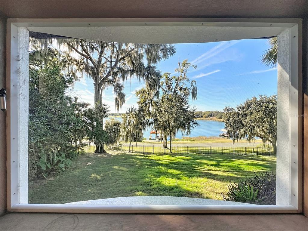 A view of a grassy yard, trees, and a lake through a window screen — 2400 TOPPING PLACE, EUSTIS, FL