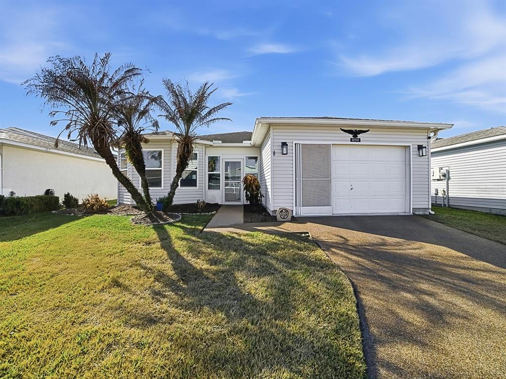 A single-story house with white siding, a garage, and a palm tree in the front yard — 32747 WESTWOOD LOOP, LEESBURG, FL