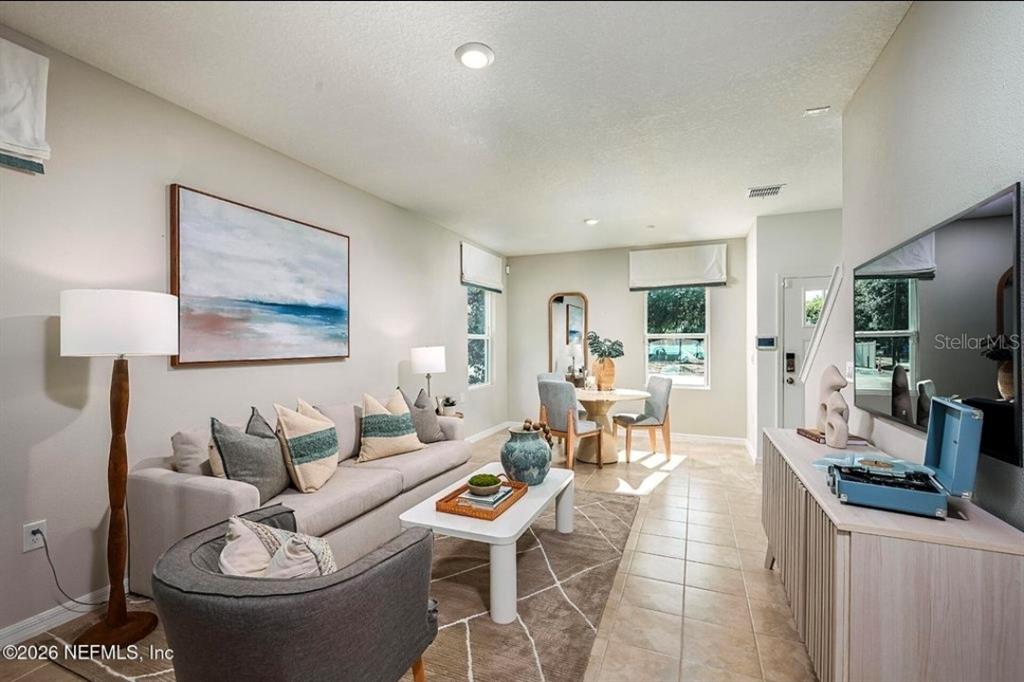 A living room features a sofa, coffee table, dining area, and a wall-mounted television — 7268 SABAL TERRACE, JACKSONVILLE, FL