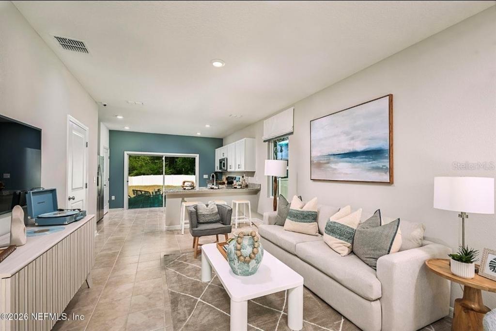 A living room with tile floors opens to a kitchen with white cabinets and counters — 7268 SABAL TERRACE, JACKSONVILLE, FL
