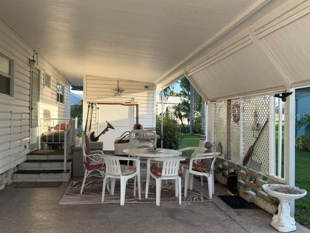 A covered patio features a dining set, a golf cart, and lattice privacy screens — 192 NEW ENGLAND AVENUE UNIT 23, PALM HARBOR, FL