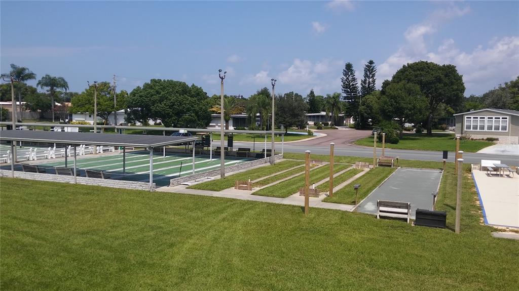 An outdoor recreational area features shuffleboard courts and a covered pavilion on a grassy lawn — 192 NEW ENGLAND AVENUE UNIT 23, PALM HARBOR, FL