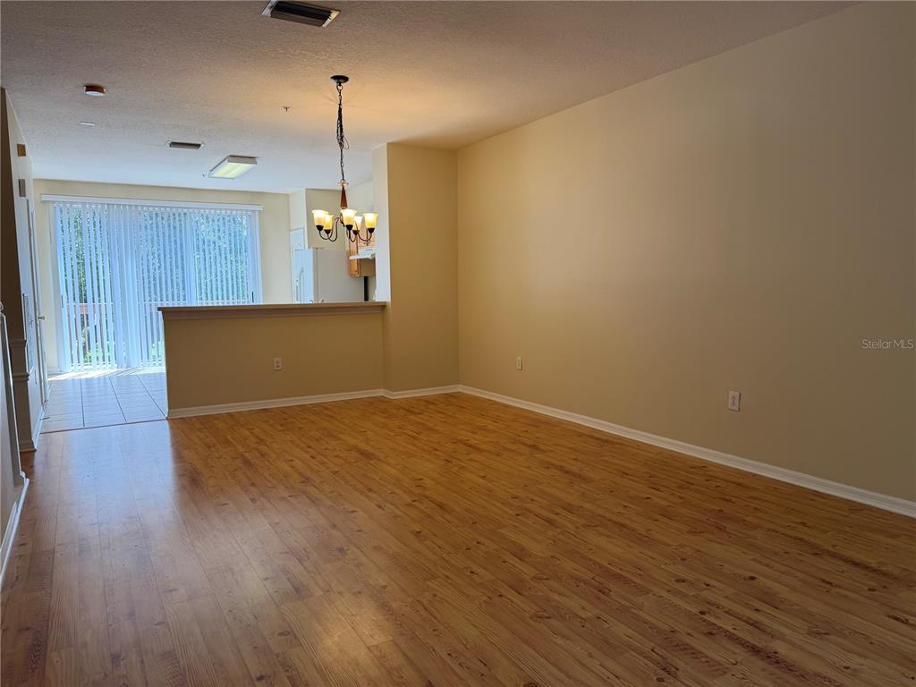 An empty living room with wood-look flooring, a breakfast bar, and a sliding glass door — 3146 BAYSHORE OAKS DRIVE, TAMPA, FL