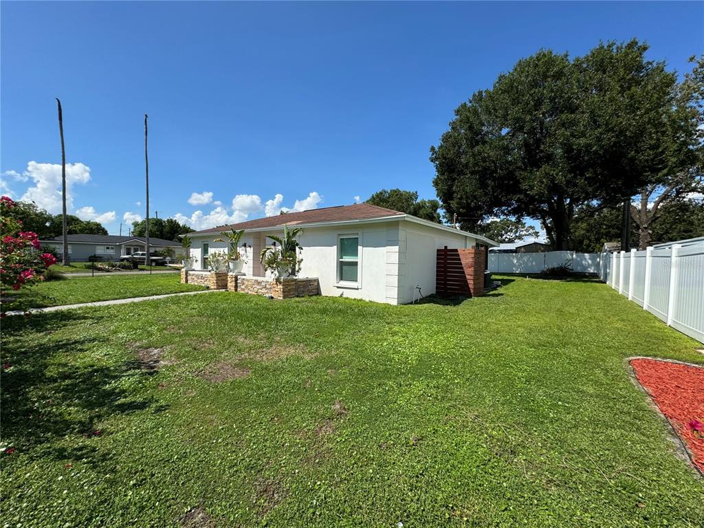 A single-story house with a white exterior, stone accents, and a large grassy yard — 7102 REINDEER ROAD, TAMPA, FL