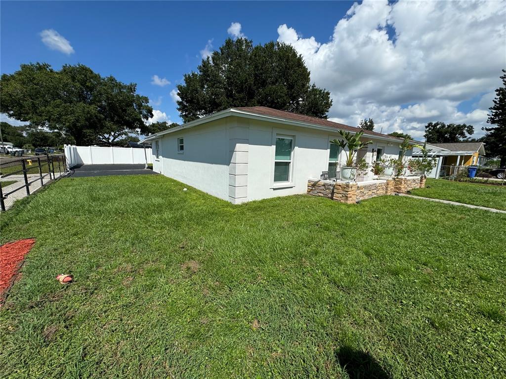 A white, single-story house with a stone-accented porch sits on a grassy lot — 7102 REINDEER ROAD, TAMPA, FL