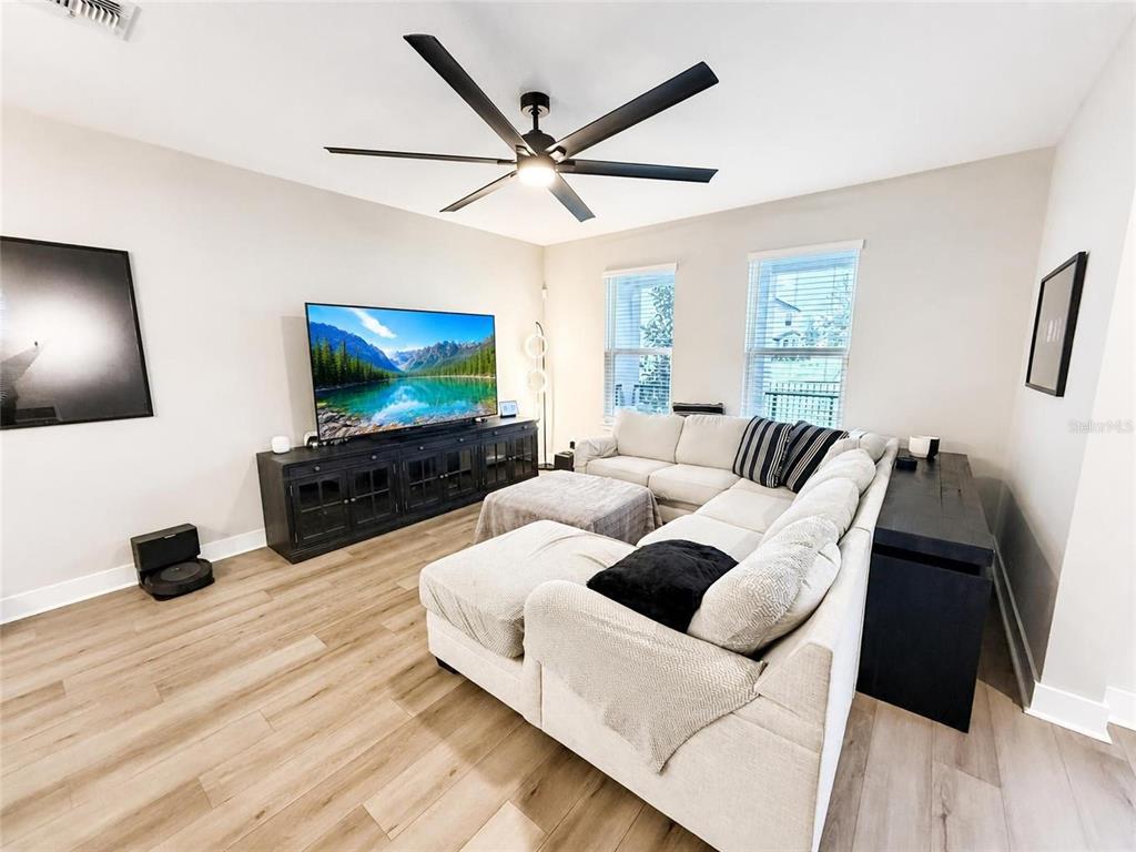 A front porch features a bright red door, a black metal railing, and a patterned mat — 4981 CORAL BEAN ALLEY, WINTER GARDEN, FL