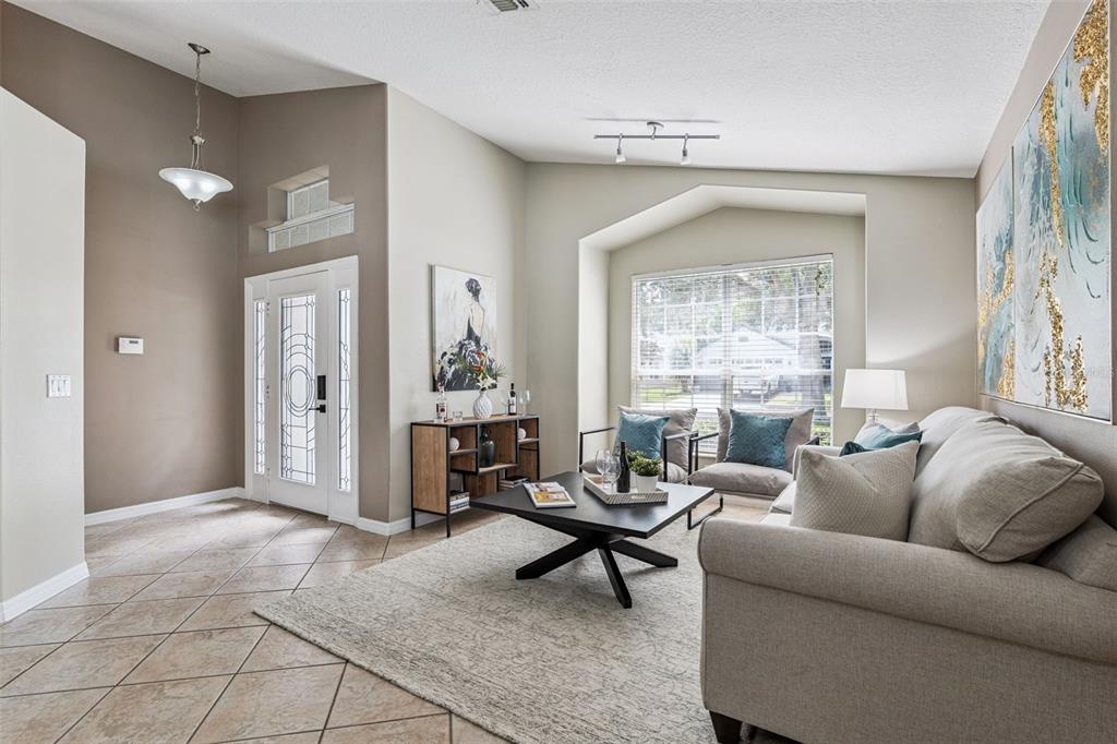A living room features a beige sofa, a black coffee table, and a tiled entryway — 1462 BARN OWL LOOP, SANFORD, FL