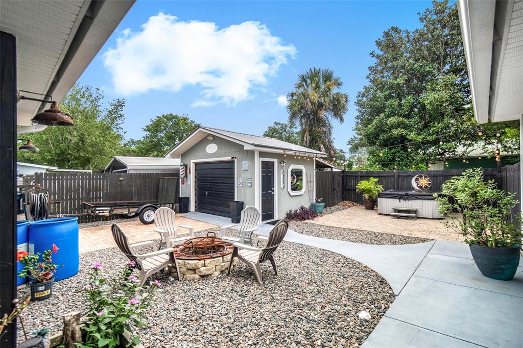 A backyard features a detached garage, a fire pit with chairs, and a hot tub — 702 N CHAPEL STREET, BUNNELL, FL
