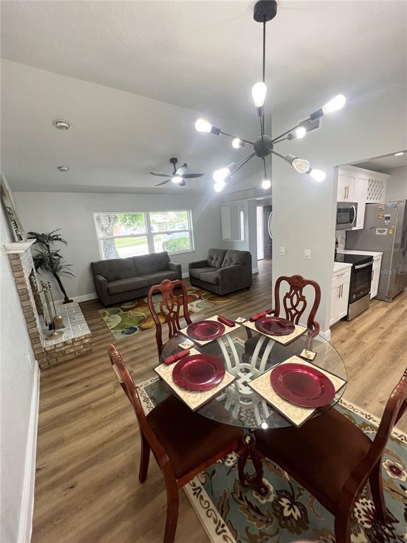 A dining area with a glass table and chandelier opens into a living room — 12195 71ST WAY, LARGO, FL