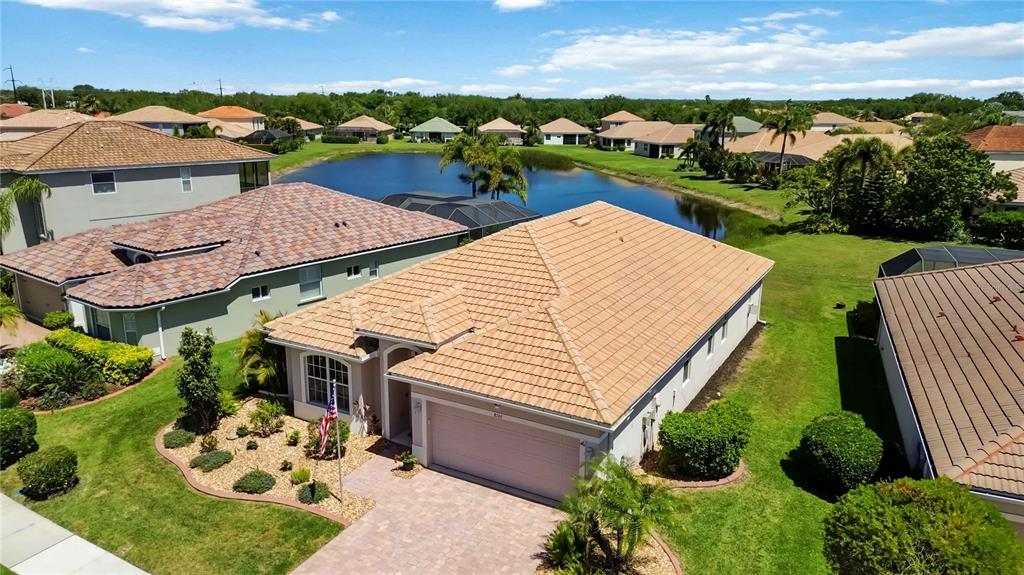 An aerial view shows a suburban house with a tan tile roof and garage — 8769 MONTEREY BAY LOOP, BRADENTON, FL