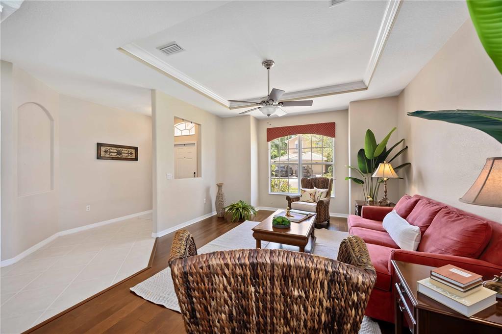 A living room with a red sofa, wooden coffee table, and an adjacent dining area — 8769 MONTEREY BAY LOOP, BRADENTON, FL