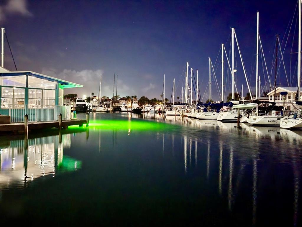 A marina at night features docked sailboats and a building illuminated by green underwater lights — 102 2ND AVENUE, VENICE, FL