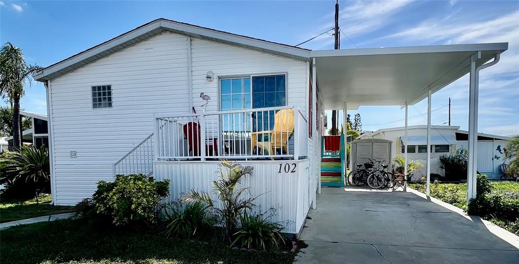 A white mobile home features a front deck, a carport, and a small storage shed — 102 2ND AVENUE, VENICE, FL